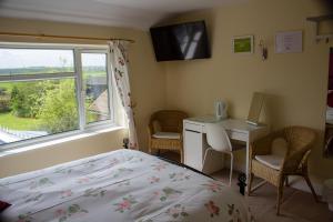 a bedroom with a bed and a desk and a window at Brambling Fields B&B in Malton
