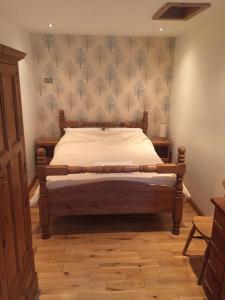 a bedroom with a bed with a wooden frame and wallpaper at The Old Vicarage Lodge in Manchester