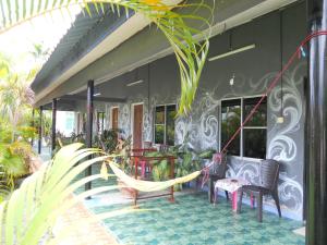 a porch with chairs and a hammock on a house at Rainbow Lodge in Pantai Cenang