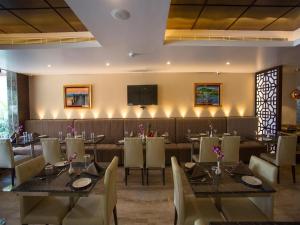 um restaurante com mesas e cadeiras e uma televisão de ecrã plano em ST Parklane Airport Hotel Chennai em Chennai