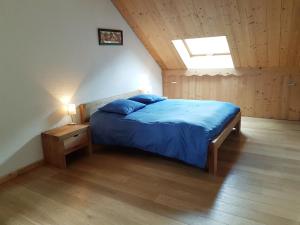 a bedroom with a bed with blue sheets and a window at L'Alpage in La Chal