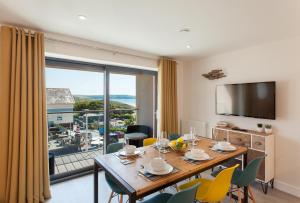 a dining room with a table and chairs and a large window at 11 Woolacombe West - Luxury Apartment at Byron Woolacombe, only 4 minute walk to Woolacombe Beach! in Woolacombe