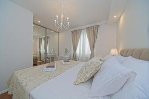 a bedroom with a large white bed with a mirror at Apartment Marangun in Ston