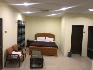 a bedroom with a bed and a couch and a chair at National City Hotel in Rawalpindi