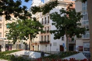 een groot wit gebouw met bomen ervoor bij Apartamentos El Marques in Málaga
