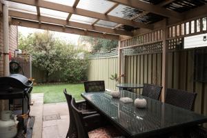 un patio con mesa, sillas y parrilla en Glenelg North " Home Away From Home", en Adelaida