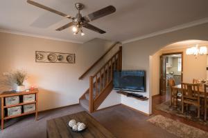 a living room with a staircase and a flat screen tv at Glenelg North " Home Away From Home" in Adelaide