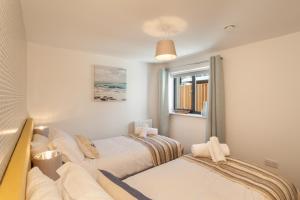 a bedroom with two beds and a window at 11 Woolacombe West - Luxury Apartment at Byron Woolacombe, only 4 minute walk to Woolacombe Beach! in Woolacombe +17 photos