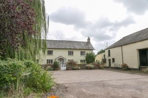 a large white house with ivy on the side of it at Lower Ford Farm in Cullompton