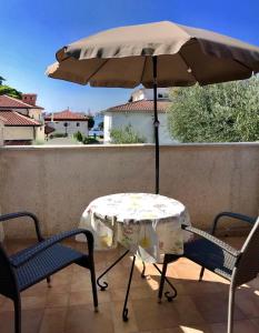 een tafel en stoelen onder een parasol op een patio bij Apartments Nadia Umag in Umag