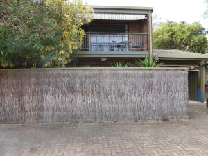 une clôture en face d'une maison avec balcon dans l'établissement Glenelg North " Home Away From Home", à Adélaïde