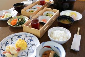 einen Tisch mit Teller mit Lebensmitteln und Schüsseln mit Lebensmitteln in der Unterkunft Hotel Shirakabaso Shigakogen in Yamanouchi