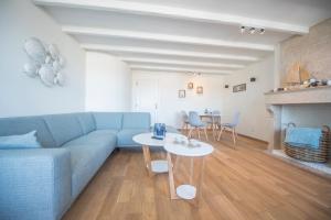 a living room with a blue couch and two tables at Point De Vue in De Haan