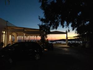 a car parked in front of a building with the sunset at Camping Koula in Parikia