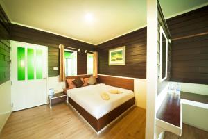 1 dormitorio con 1 cama en una habitación con paredes de madera en Hatthatara Resort en Samut Songkhram