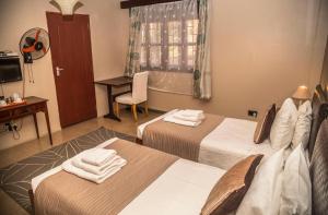 a hotel room with two beds and a desk at Papaya Holiday Home in Kampala