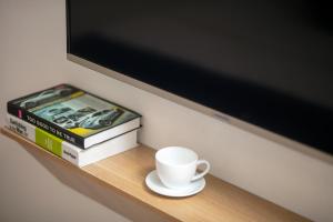 a cup of coffee on a shelf with books and a tv at Hanoi Golden Hotel in Hanoi