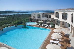 a swimming pool with umbrellas in front of a house at Petra Bianca in Porto Cervo
