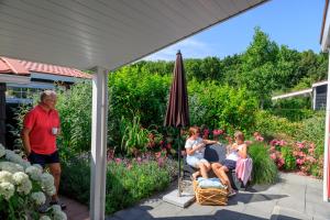 un grupo de personas sentadas en un patio bajo una sombrilla en Vakantiepark de Meerpaal, en Zoutelande