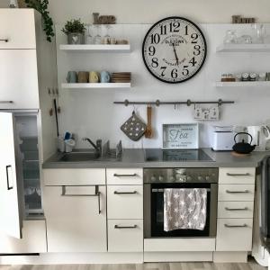 a kitchen with a clock on the wall and a stove at Friesenhof in Friedrichskoog