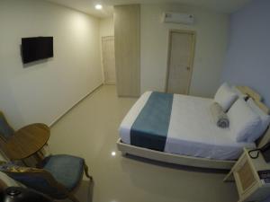 a bedroom with a bed and a chair and a television at Hotel Med Centro - Marcari in Barranquilla