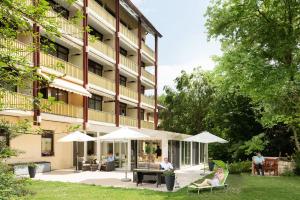 a hotel with people sitting under umbrellas in front of a building at Appartment Hotel Victoria in Bad Füssing