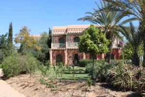 une maison en briques avec un palmier en face de celle-ci dans l'établissement Palmeraie village, à Marrakech
