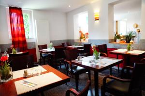 un restaurant avec des tables et des chaises en bois et des rideaux rouges dans l'établissement Hotel am Tierpark, à Güstrow
