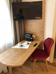 a wooden table with a chair and a television on a wall at Hotel Walser in Ulrichen