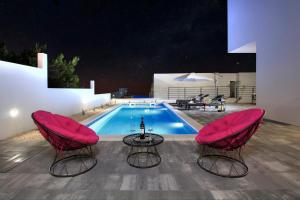 a pool with two pink chairs and a table and a pool at Villa Navis HEATED POOL in Makarska
