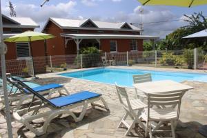 a swimming pool with chairs and a table and a house at Résidence les Kalbassiers in Lamentin