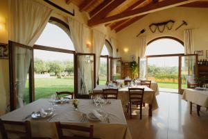 un restaurante con mesas y sillas blancas y ventanas grandes en Agriturismo Spigolo, en Avesa