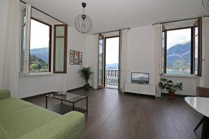 un soggiorno con ampie finestre e un divano verde di palazzo barindelli suite verde a Bellagio