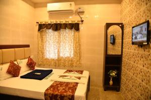 Cette chambre comprend un lit, une télévision et une fenêtre. dans l'établissement Rightchoicehotels, à Rameswaram