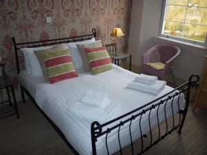 um quarto com uma cama grande com lençóis brancos e almofadas em Royal Oak Inn em Lostwithiel