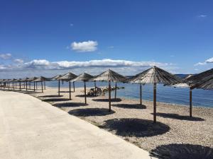 a row of umbrellas on a beach next to the water at Harmony VIR Luxuriös ausgestattete Ferienwohnung mit 65m2 in Vir