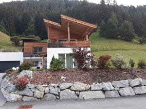 ein Haus auf einem Hügel mit einer Steinmauer in der Unterkunft Apart Silke in Pettneu am Arlberg