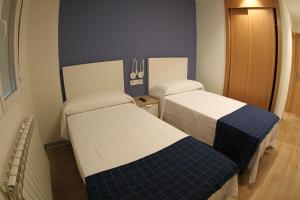 two beds in a small room with blue and white at Hostal Mónaco in Valladolid