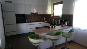 a kitchen with white cabinets and green bar stools at La Petite Fleur in Enges