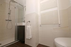 y baño blanco con ducha y aseo. en palazzo barindelli suite bianca en Bellagio