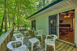 a porch with white chairs and a table and a piano at Nantahala Cabins in Bryson City