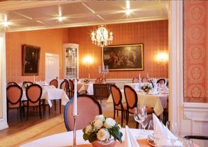 a dining room with tables and chairs and a chandelier at Hotel Schloss Wilkinghege in Münster