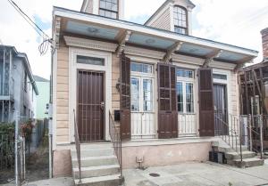 una pequeña casa con puertas marrones y escaleras en una calle en Perfect NOLA Hideaway en Nueva Orleans