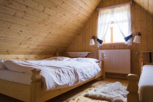 ein Schlafzimmer mit einem Bett in einem Holzzimmer in der Unterkunft Pienińskie Herbarium zdrowie i dobre samopoczucie in Grywałd