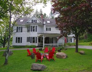 a group of red chairs in front of a white house at The Wilmington Inn in Wilmington