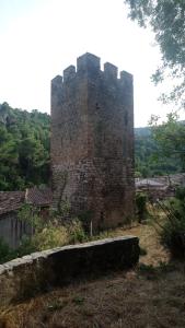 a tall brick castle with a stone wall in a field at Gîte de La Tour in Saint-Guilhem-le-Désert