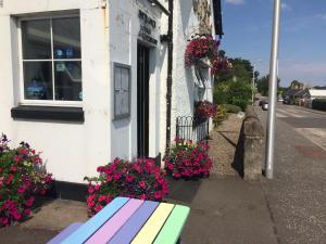 un banco sentado fuera de un edificio con flores en Glencarse Hotel, en Glencarse