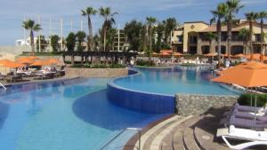 una gran piscina con sillas y sombrillas en un complejo en Suites at PB Sunset Beach Golf and Spa Cabo San Lucas, en Cabo San Lucas