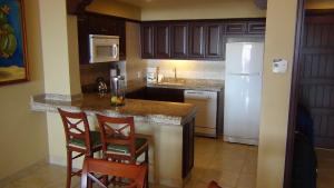 a kitchen with a counter and a white refrigerator at Suites at PB Sunset Beach Cabo San Lucas in Cabo San Lucas