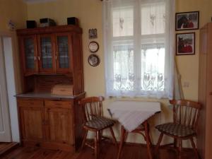 cocina con mesa, 2 sillas y ventana en Domek Drewniany, en Nowa Wola